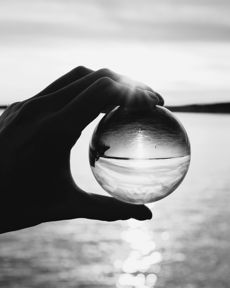 Clarity in Decision Making Creates Strategic Perspective Hand holding a glass sphere symbolizing clarity, foresight, and strategic decision making in business leadership.